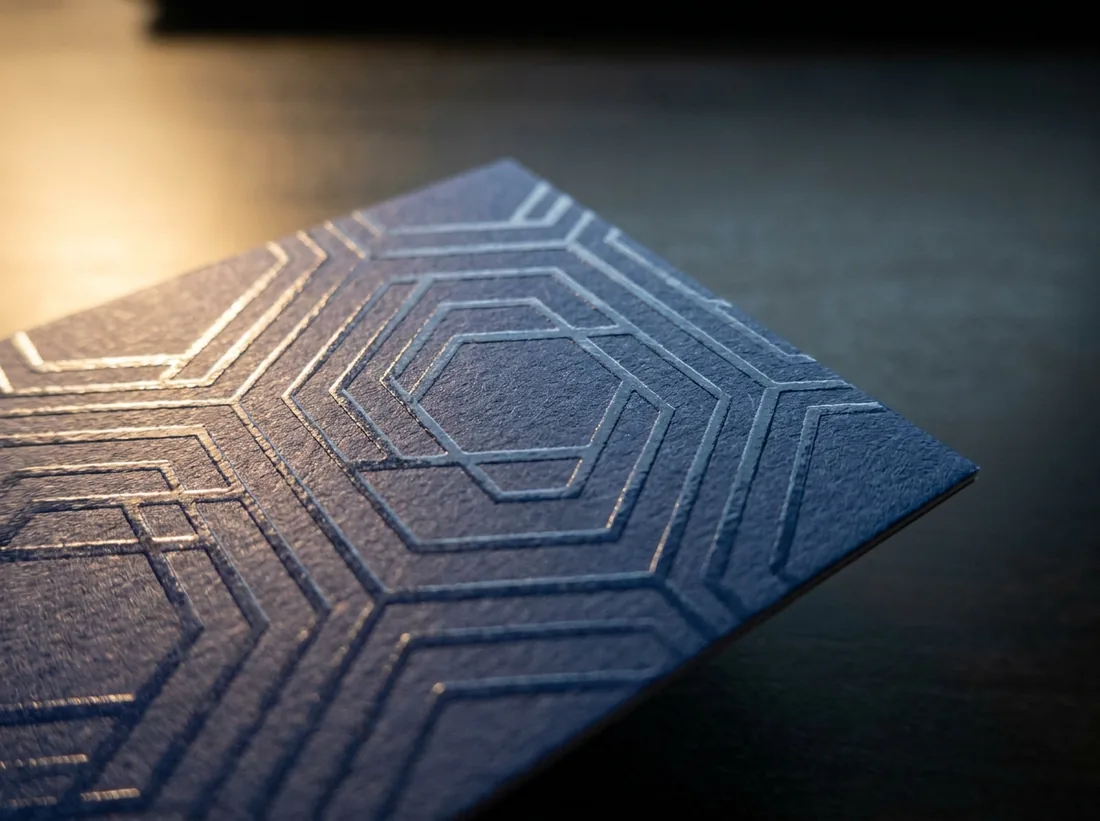 Raised spot UV hexagon pattern catching the light on a matte navy business card